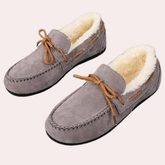 Graue Wildleder-Hausschuhe mit Fellfutter und braunen Schnürsenkeln, gemütliche Wintermode.