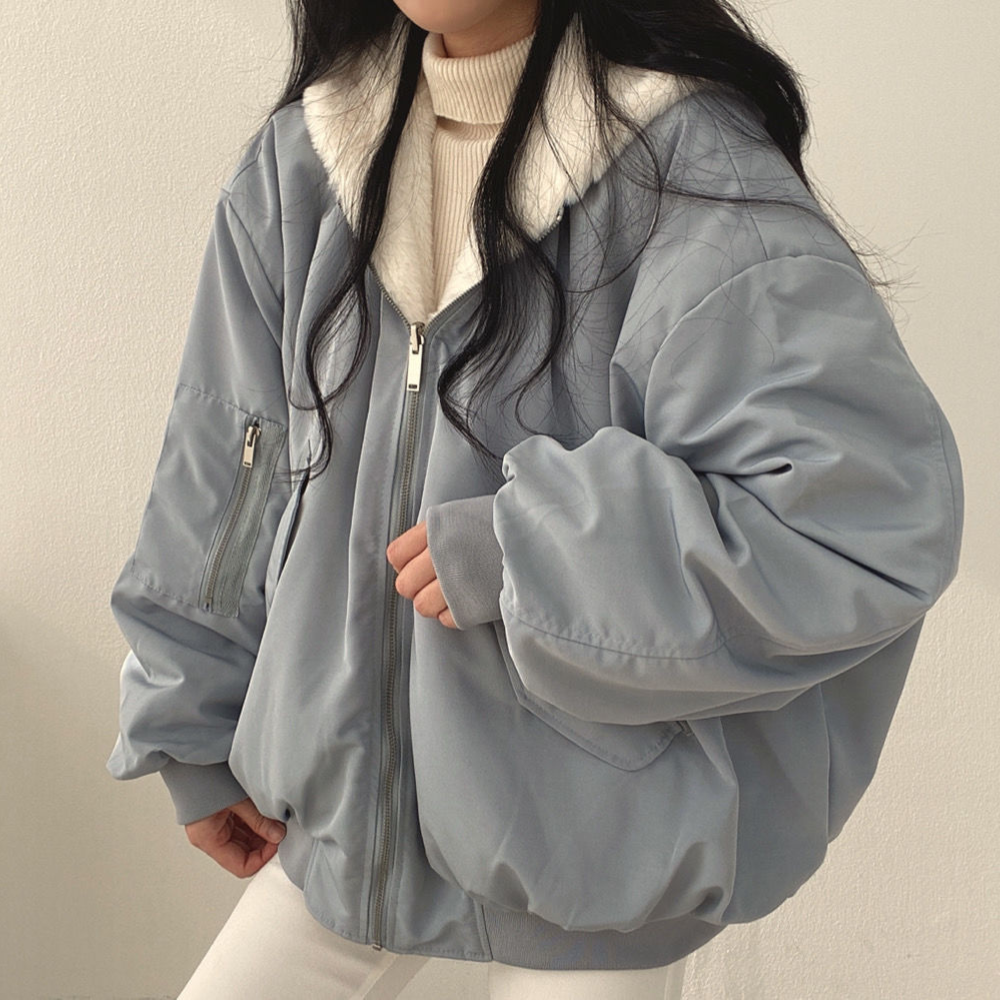 Frau in blauer Oversize-Jacke mit Reißverschluss und weißem Kragen, modisch, Winterkleidung.