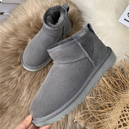 Graue Winterstiefel aus Wildleder mit Fellfutter auf Fellteppich.