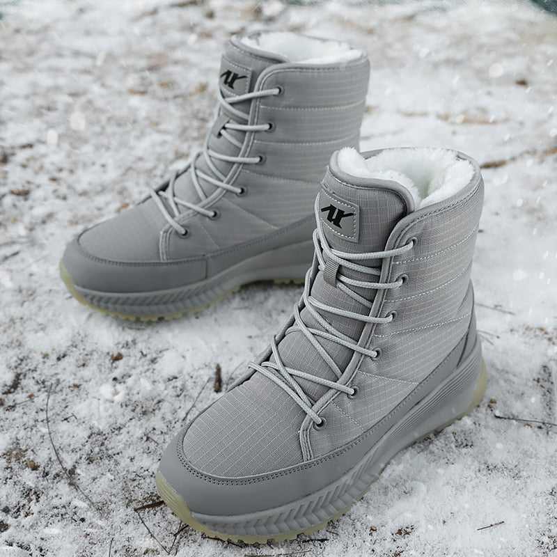 Graue Winterstiefel mit Schnürung, wasserdicht, gefüttert, auf schneebedecktem Boden.