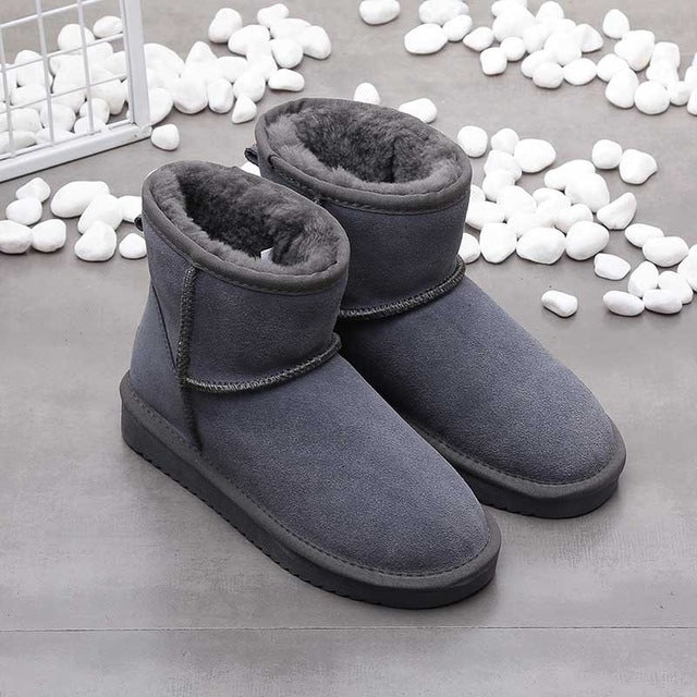 Graue Winterstiefel aus Wildleder mit Fellfutter auf grauem Hintergrund, warme Damenstiefel.