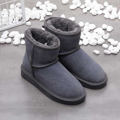 Graue Winterstiefel aus Wildleder mit Fellfutter auf grauem Hintergrund, warme Damenstiefel.