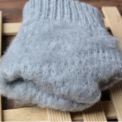 Grauer Wollschal aus Alpaka, weich und warm, auf Holzuntergrund, ideal für kalte Wintertage.