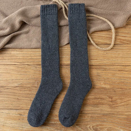 Graue Wollkniestrümpfe auf Holzboden, warme Winterstrümpfe, gemütliche Socken.