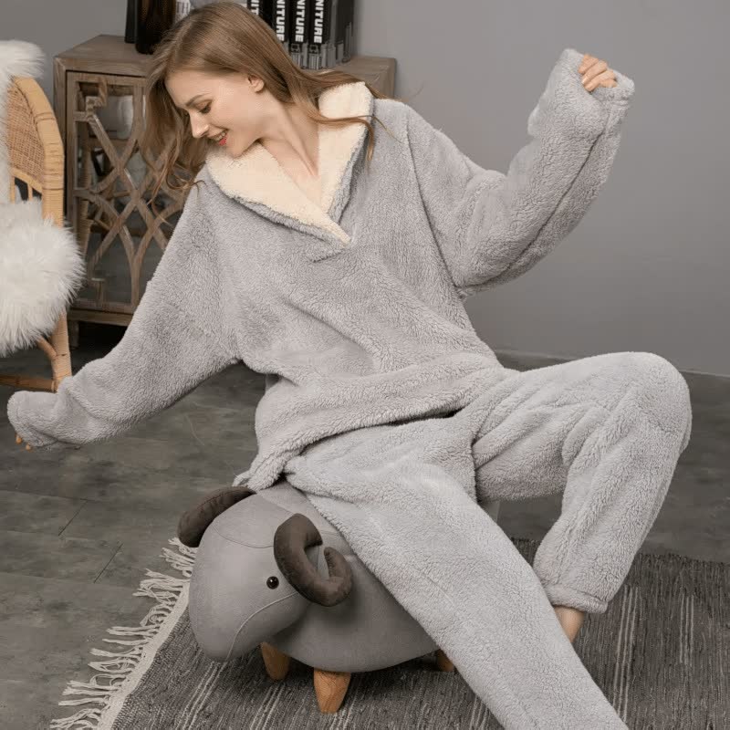 Frau in grauem Fleece-Hoodie und Hose sitzt auf einem Hocker in Schafform, gemütliche Kleidung.