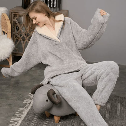 Frau in grauem Fleece-Hoodie und Hose sitzt auf einem Hocker in Schafform, gemütliche Kleidung.