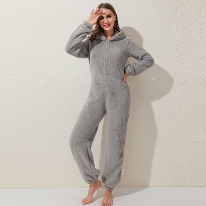 Frau in grauem Fleece-Overall mit Kapuze, gemütlicher Einteiler, Freizeitkleidung.