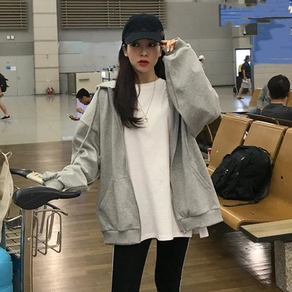 Frau in grauem Hoodie und schwarzer Kappe im Flughafen, lässige Mode, Reisekleidung.