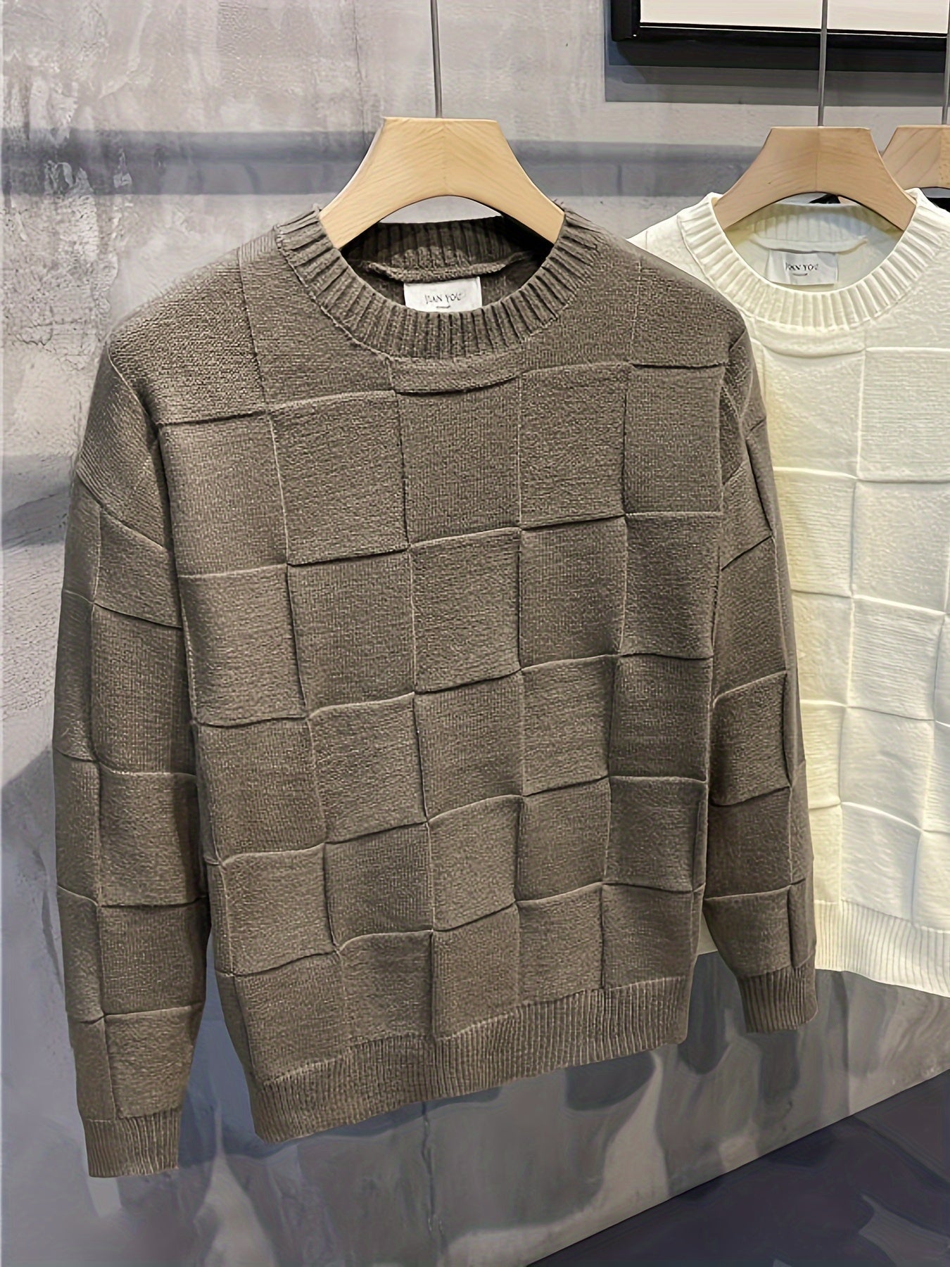 Grauer Strickpullover mit Karomuster, Herrenmode, Baumwolle, Herbst-Winter, auf Holzkleiderbügel.