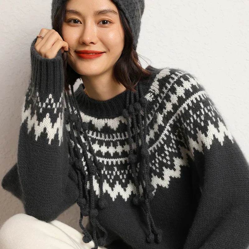 Frau in grauem Strickpullover mit Norwegermuster und Mütze, lächelnd, Wintermode.