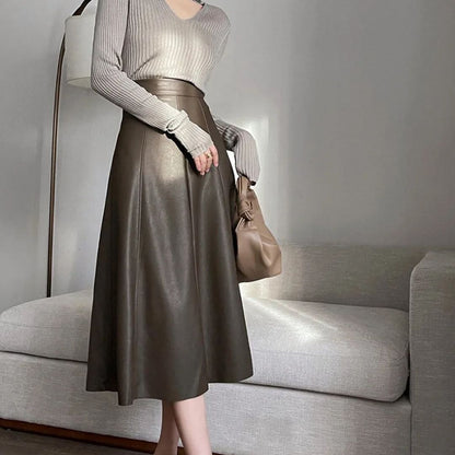 Damenmode: Grauer Pullover, brauner Lederrock, eleganter Look, Wohnzimmer, Herbstmode.