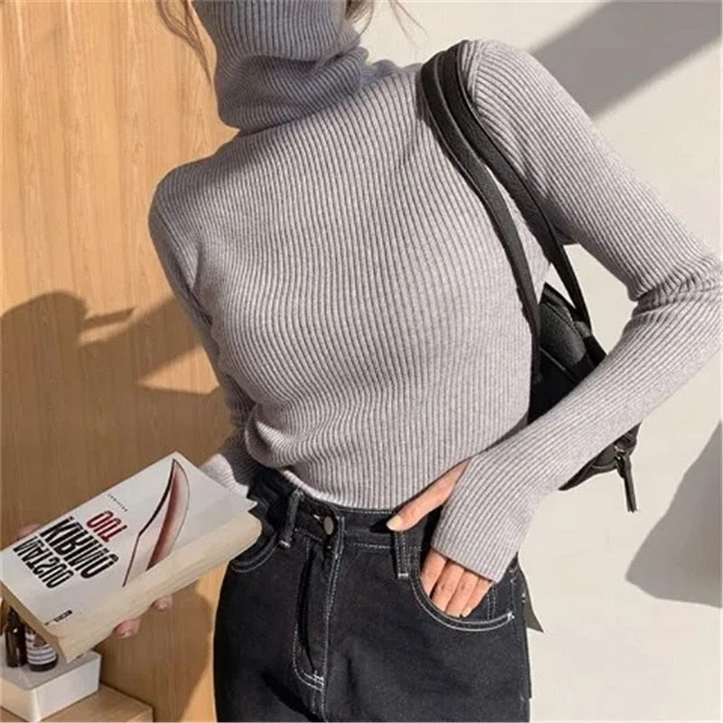 Frau in grauem Rollkragenpullover, schwarze Jeans, Buch, Sonnenlicht, modisch, Herbstmode.