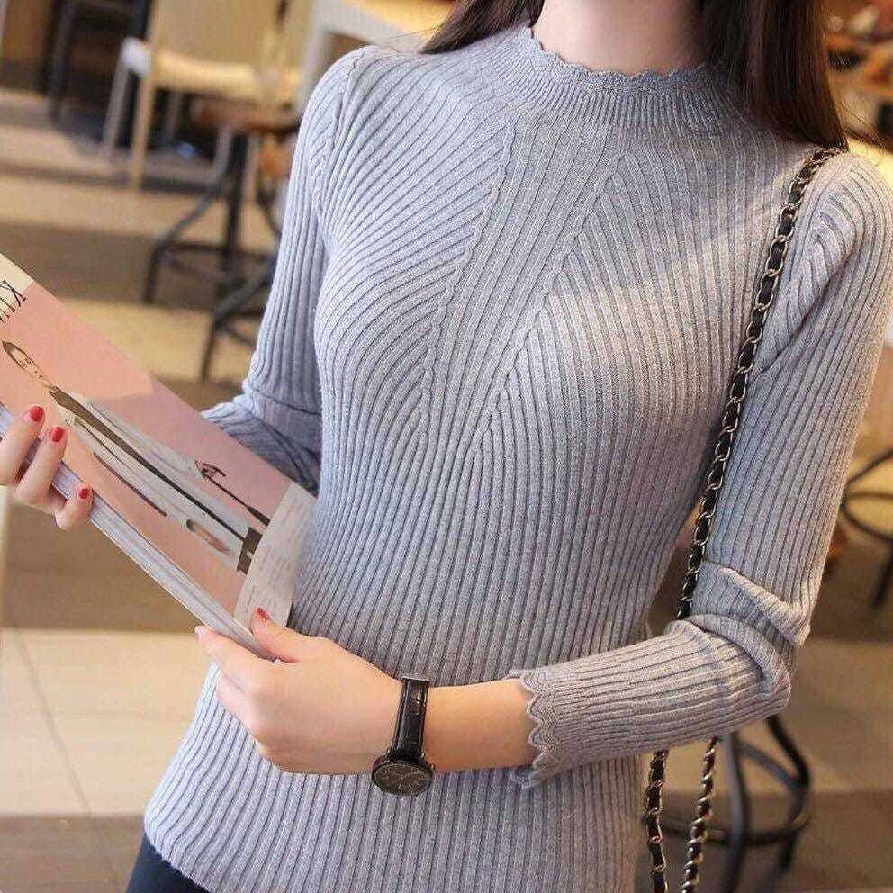 Frau in grauem, geripptem Strickpullover mit Uhr und Magazin in modernem Café.