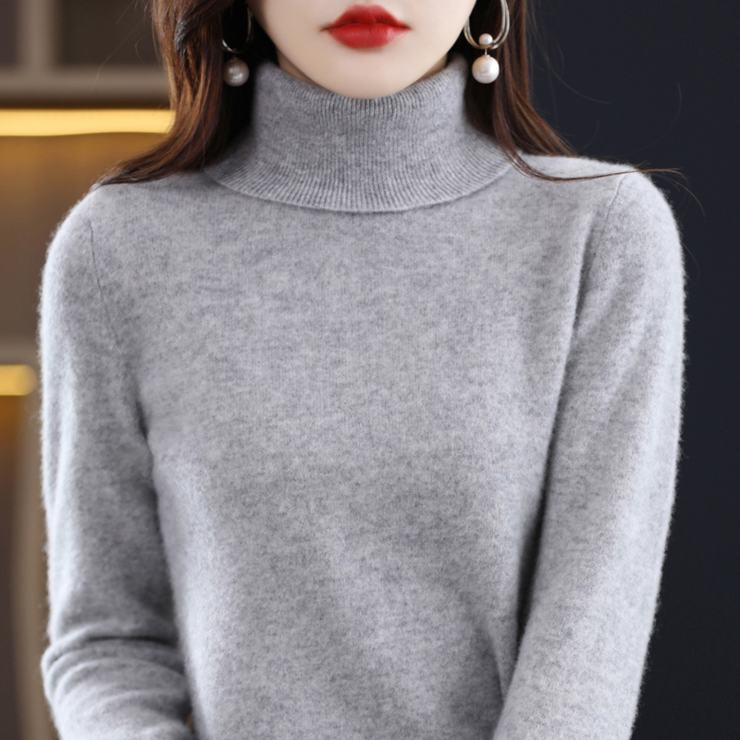 Frau in grauem Rollkragenpullover aus Kaschmir, elegante Ohrringe, Mode, Herbst-Winter-Look.