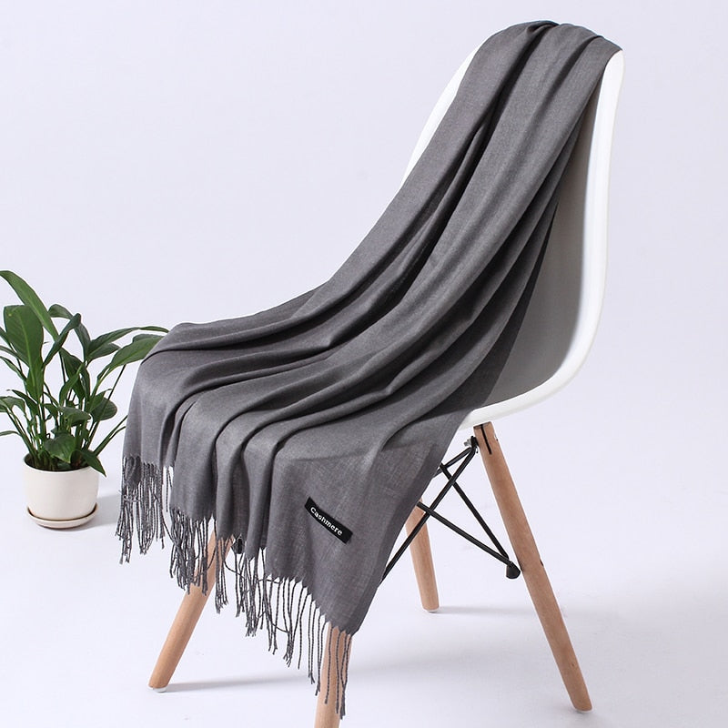 Grauer Kaschmirschal auf weißem Stuhl, weiches Material, modisches Accessoire, Wohnzimmer.
