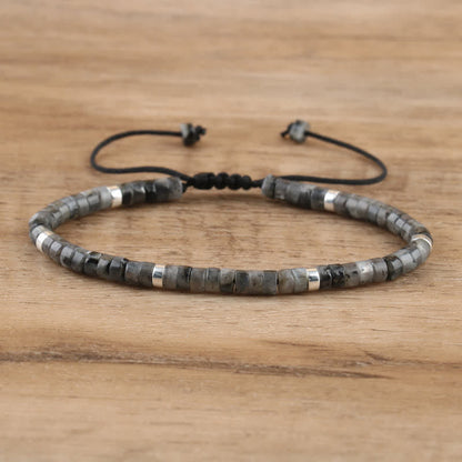 Armband aus grauen und silbernen Perlen, verstellbar, handgefertigt, auf Holzoberfläche.