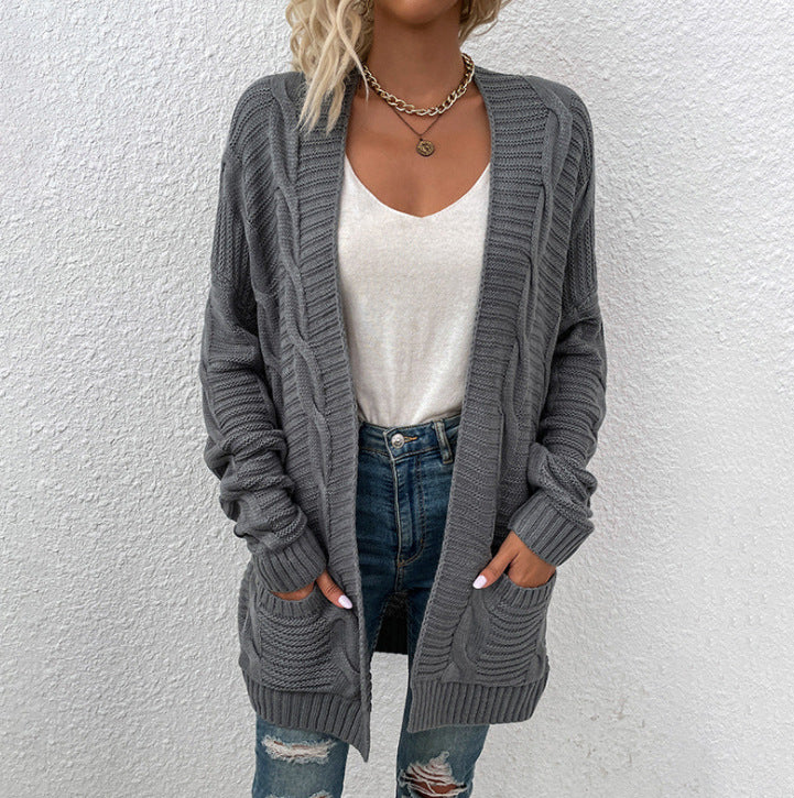 Frau in grauem Strickcardigan, weiße Bluse, zerrissene Jeans, lässiger Herbstlook.