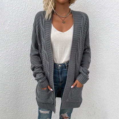 Frau in grauem Strickcardigan, weiße Bluse, zerrissene Jeans, lässiger Herbstlook.