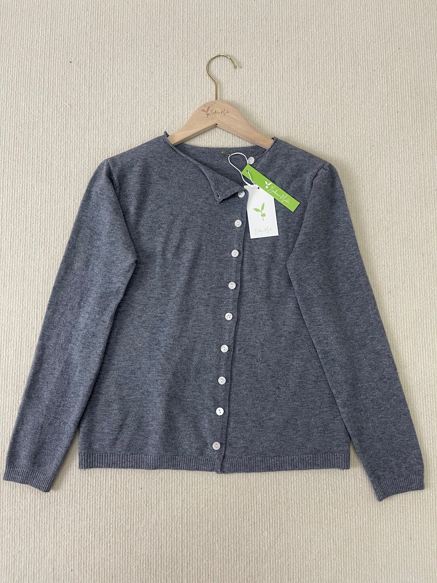Grauer Damen-Cardigan aus Wolle, Knopfleiste, nachhaltige Mode, auf Holzkleiderbügel.