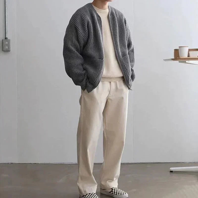 Mann in grauer Strickjacke und beiger Hose, lässige Mode, minimalistisch, modern.