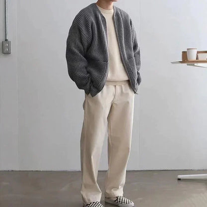 Mann in grauer Strickjacke und beiger Hose, lässige Mode, minimalistisch, modern.