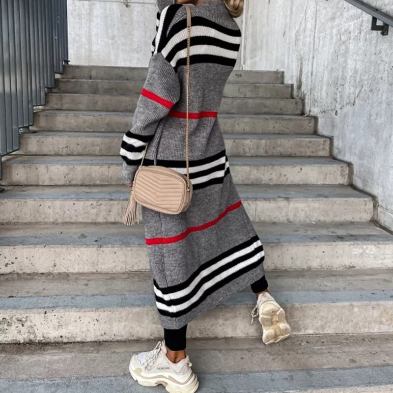 Frau in grauem Strickkleid mit Streifen, beige Umhängetasche, Treppe, modisch, urban.