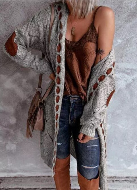 Frau in grauem Strickcardigan mit braunen Ellbogenpatches, Jeans und braunem Top.