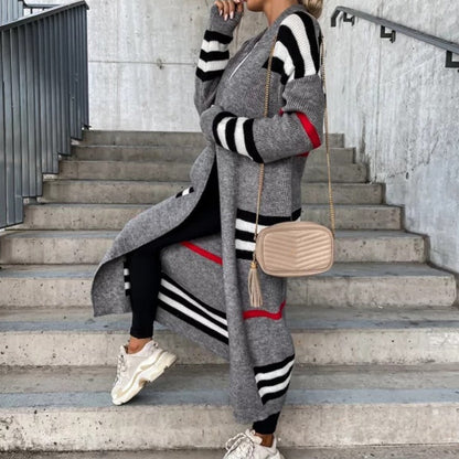 Frau in grauem Strickmantel mit Streifen, beige Umhängetasche, weiße Sneaker, Treppe.