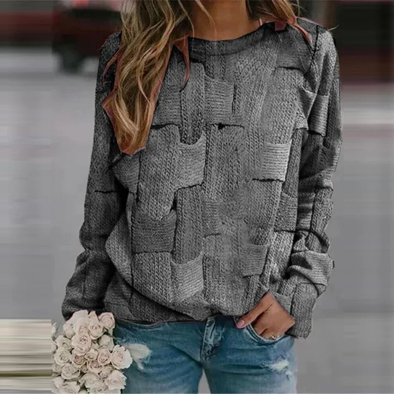 Frau in grauem Strickpullover mit Zopfmuster, hält weiße Rosen, trägt blaue Jeans.