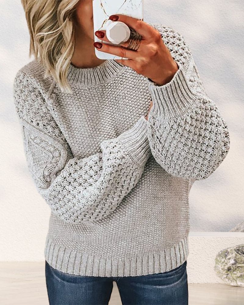 Frau in grauem Strickpullover mit Zopfmuster, lässiger Stil, Herbstmode, Nahaufnahme.