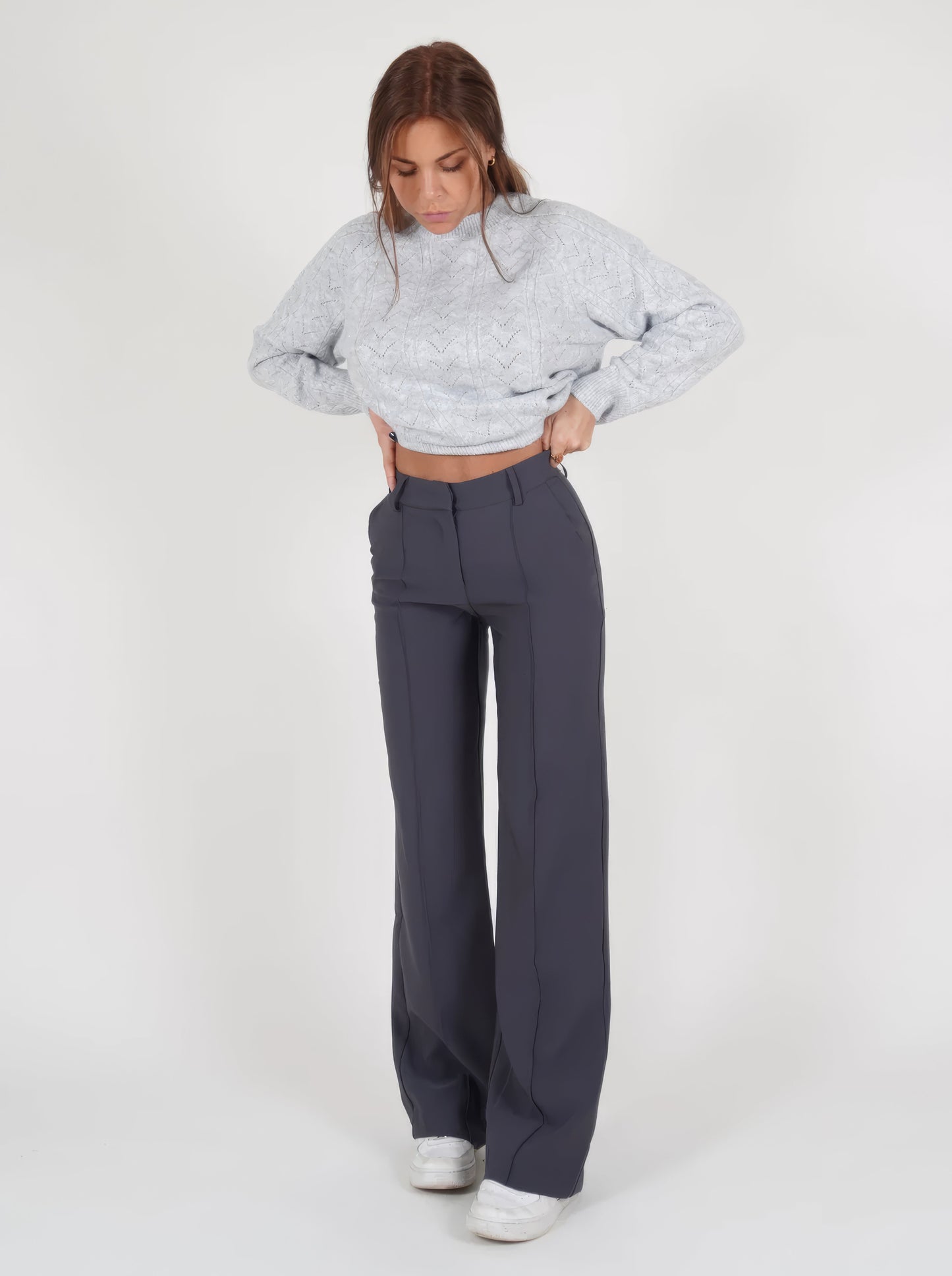 Frau in grauem Strickpullover und dunkelgrauer Hose, modische Damenbekleidung, Wintermode.