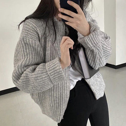 Frau in grauem Strickpullover, hält Smartphone, modisch, gemütlich, Herbstmode, Innenraum.