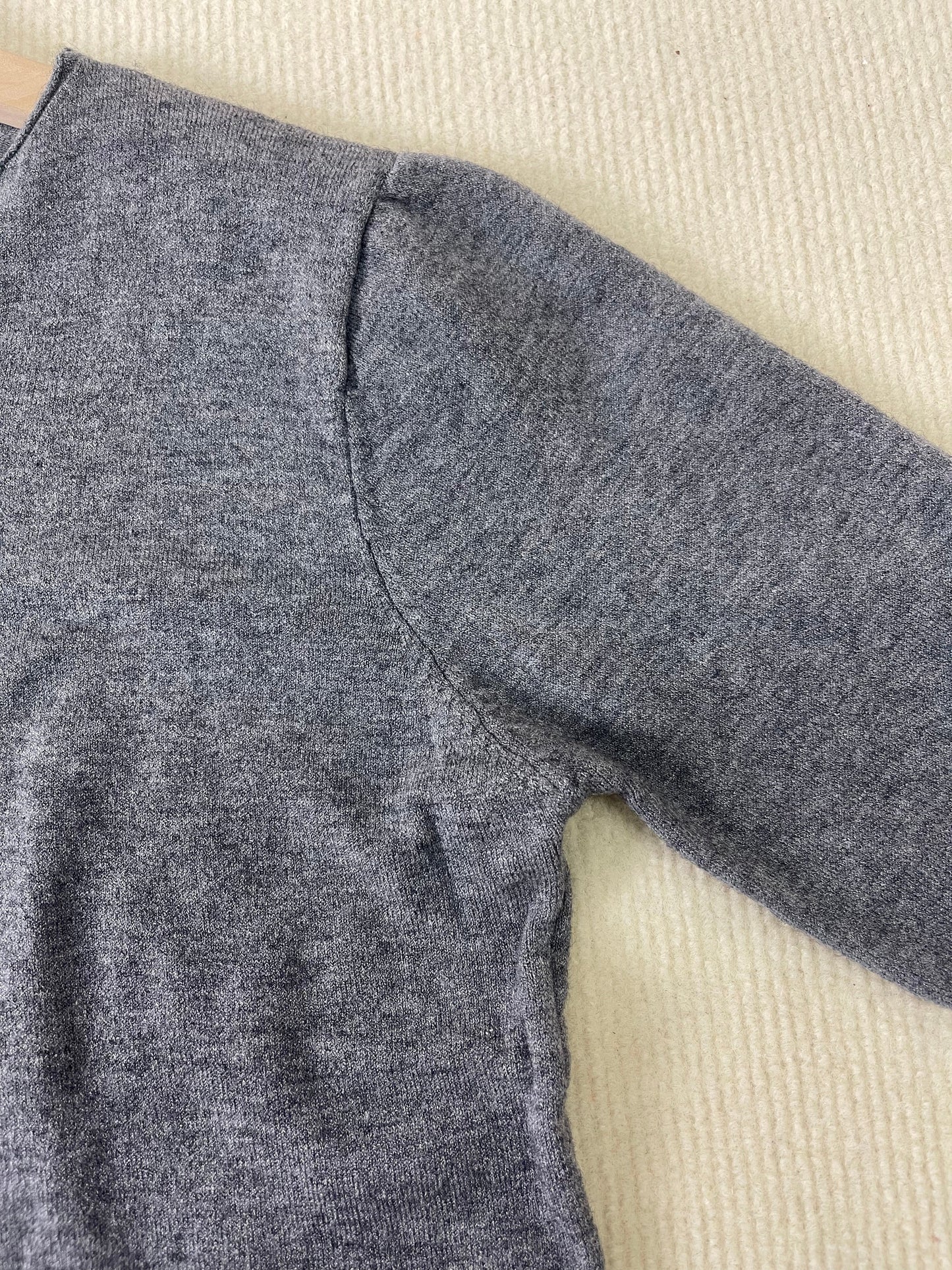Grauer Wollpullover, Nahaufnahme, weiches Material, langärmeliger Strick, gemütliche Herbstmode.