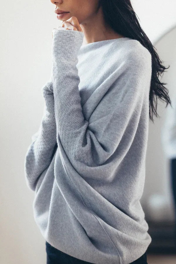 Frau trägt grauen Oversize-Pullover aus Kaschmir, gemütliche Wintermode, elegantes Design.