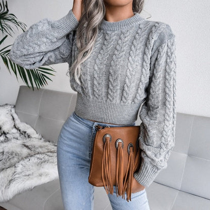 Frau in grauem Strickpullover mit brauner Fransenhandtasche, modisch, gemütlich, Wohnzimmer.