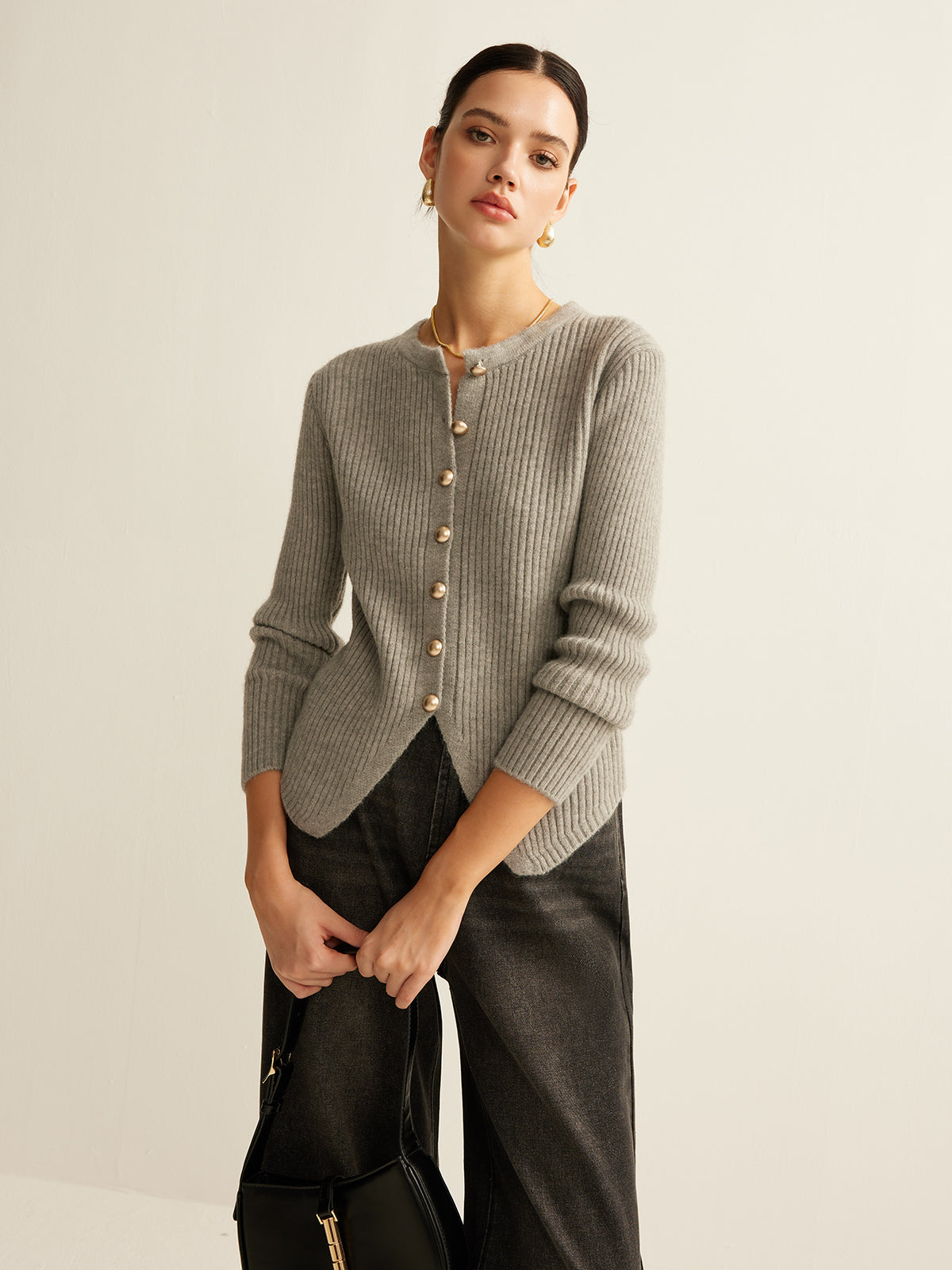 Frau in grauem Strickpullover mit Knöpfen, schwarze Hose, eleganter Look, Modefotografie.