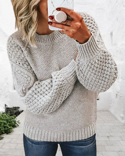 Frau in grauem Strickpullover mit Zopfmuster, lässig, modisch, Herbstmode, gemütlich.