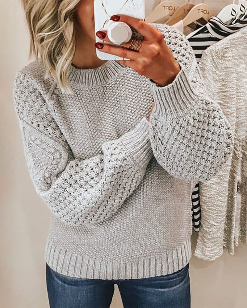 Frau in grauem Strickpullover mit Zopfmuster, lässiger Look, Herbstmode, gemütlich.