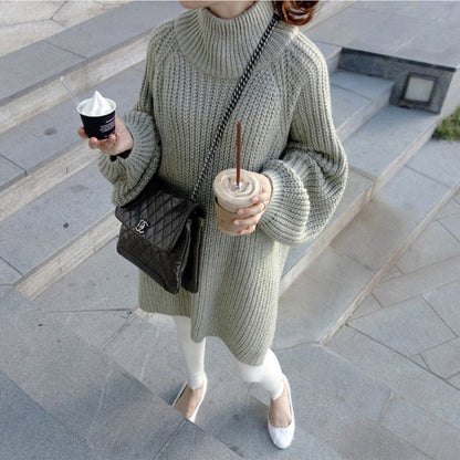 Frau in grauem Strickpullover, hält Kaffee und Eis, trägt schwarze Umhängetasche, weiße Hose.