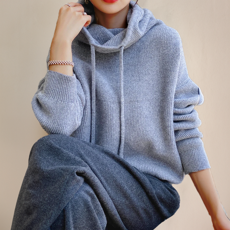 Frau in grauem Strickpullover mit Kapuze und Kordeln, lässiger Stil, gemütliche Herbstmode.