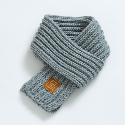 Grauer Strickschal mit Lederetikett, modisches Accessoire, warm, weich, Winterkleidung.