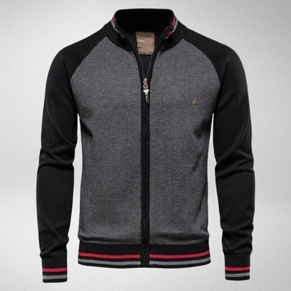 Graue Herrenjacke mit schwarzem Kragen, Reißverschluss, rot-schwarzen Streifen, sportlich.