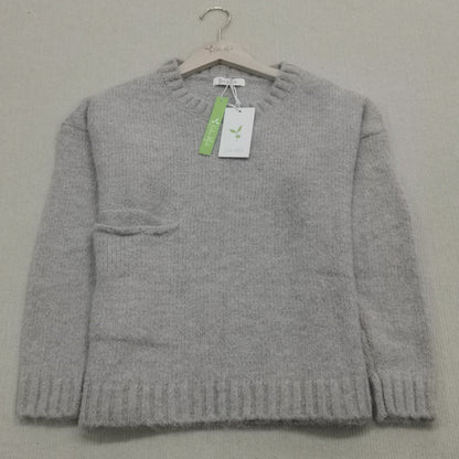Grauer Wollpullover auf Bügel, Rundhalsausschnitt, Etikett, weiches Material, Damenmode.