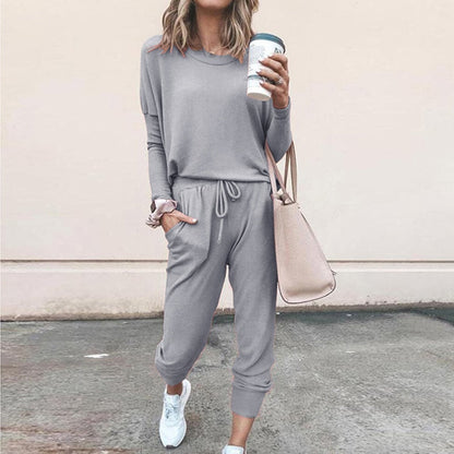Frau in grauem Jogginganzug mit Kaffeebecher und beiger Tasche, lässige Mode.