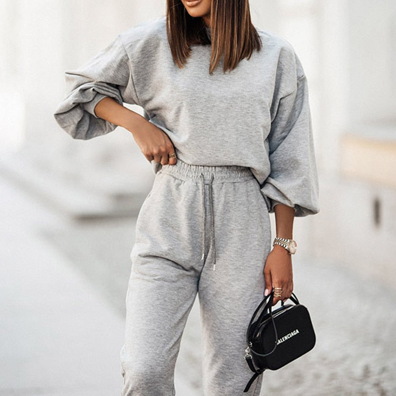Frau in grauem Jogginganzug, hält schwarze Tasche, modisch, lässig, Streetwear.