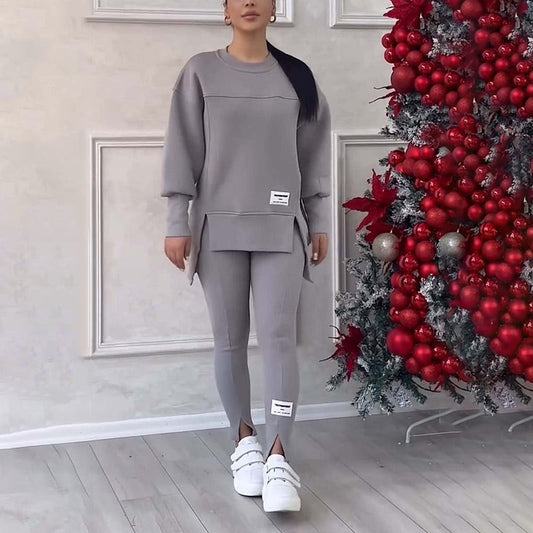 Frau in grauem Trainingsanzug neben Weihnachtsbaum mit roten Kugeln, weiße Sneaker.