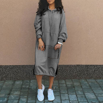 Frau in grauem Kapuzenkleid, lässig, mit weißen Sneakers, modisch, urbaner Stil.