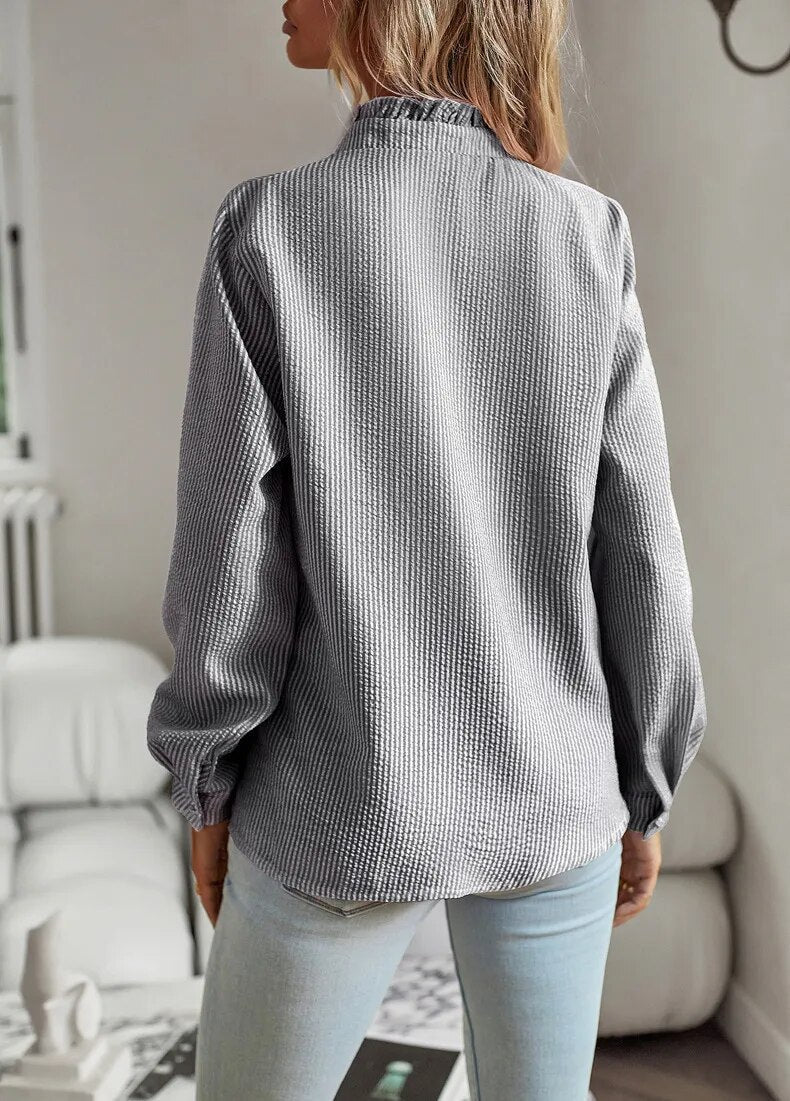 Frau in grauer Strickbluse und blauer Jeans, modisch, lässig, Innenraum.