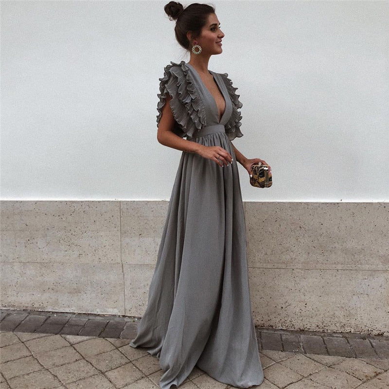 Frau in grauem Abendkleid mit Rüschen, elegantes Design, modisches Outfit, festliche Kleidung.