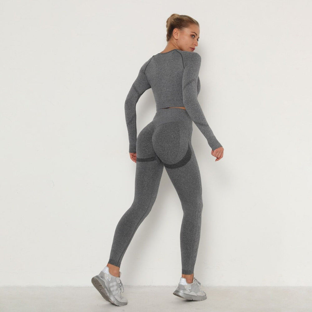 Frau in grauem nahtlosem Sport-Set, Langarm-Top und Leggings, Fitnessmode, Rückansicht.